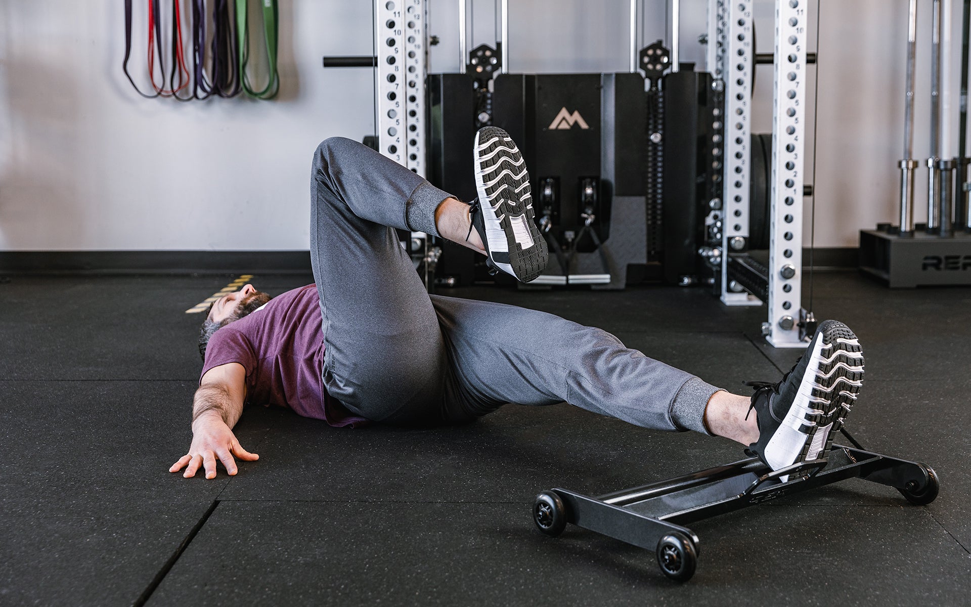 Athlete doing exercises with 1 foot on the glute ham roller.