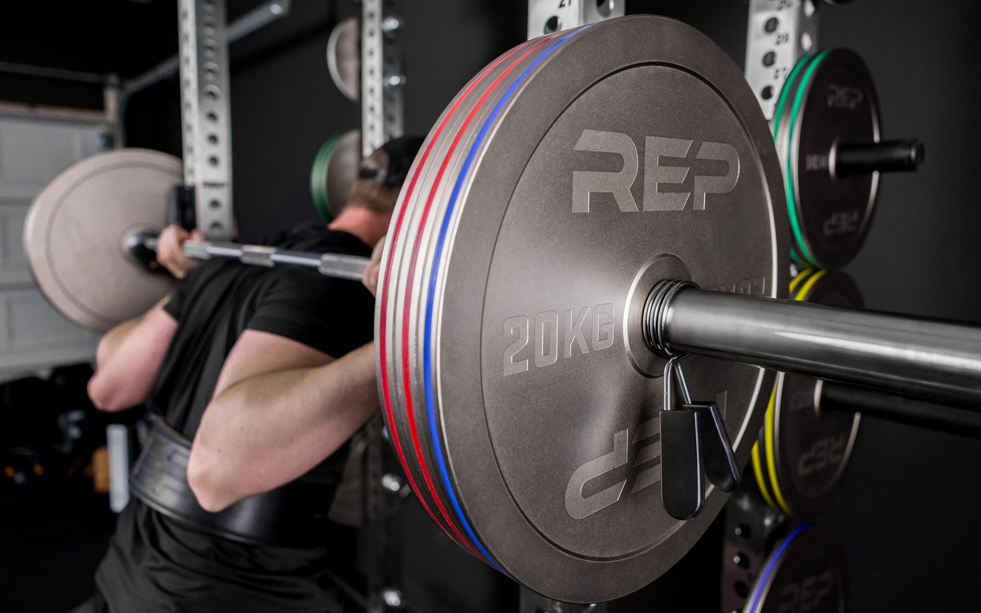 Athlete squatting with Rep Fitness Calibrated Steel Plates (KG), highlighting their thin size and IPF Specs for powerlifting
