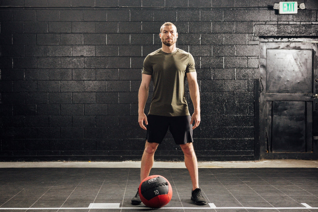 Athlete stands above a medicine ball in REP apparel.